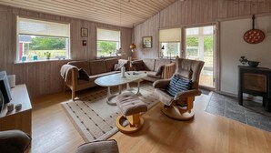 En hyggelig stue med sofa, lænestole, sofabord og pejs.