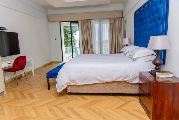 A hotel room with a bed, a desk, a TV, and a view of the outdoors.