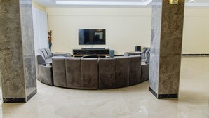 Una sala de estar moderna con un sofá gris curvo, un televisor de pantalla plana y una mesa de centro.