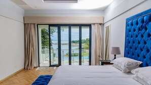 Un dormitorio con una cama grande, vistas a un cuerpo de agua y un balcón.