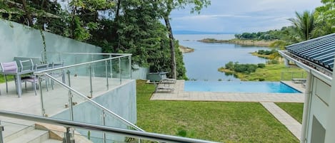 Un espacio exterior moderno con piscina, escaleras y vistas a un lago.