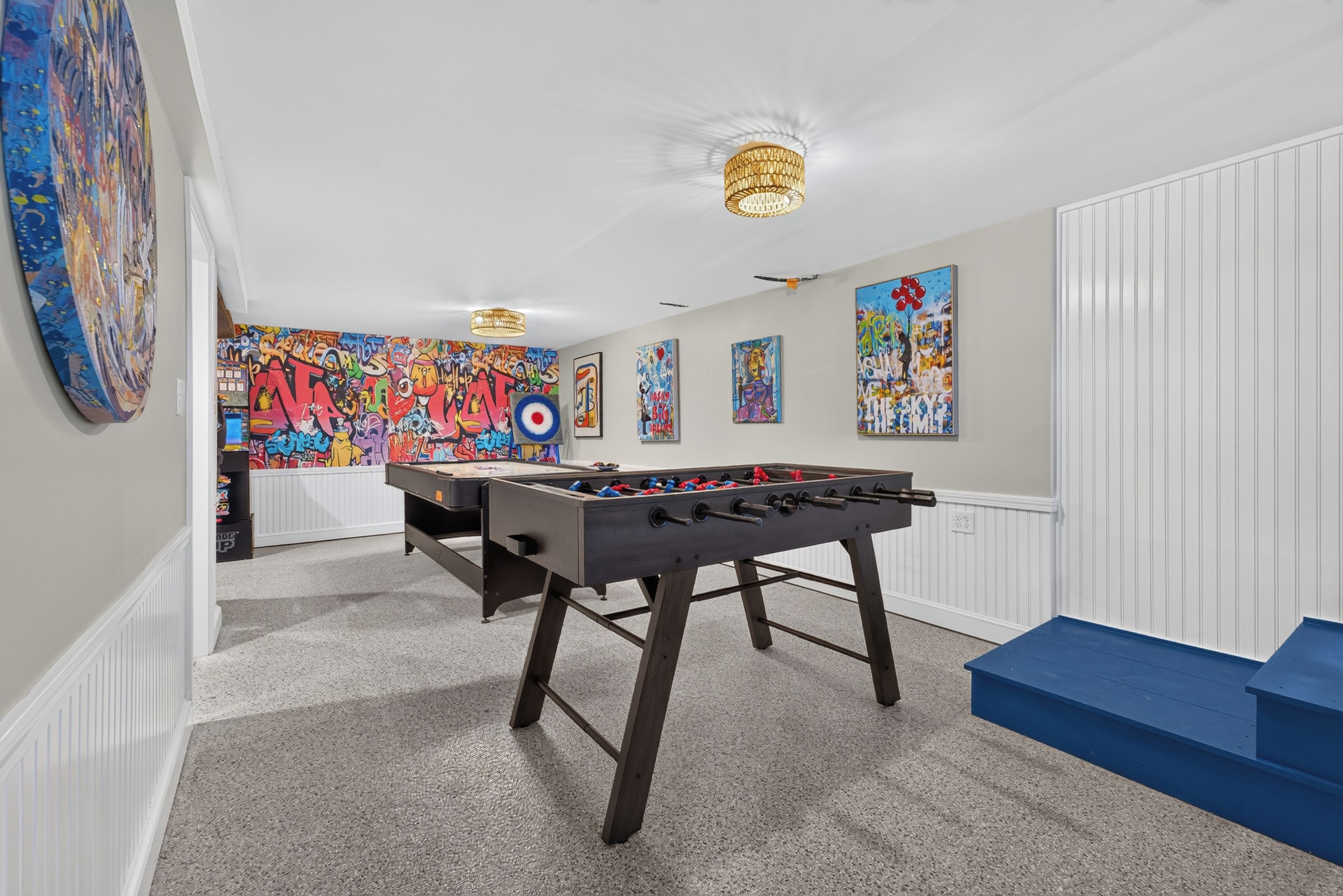 Ein Zimmer mit einem Kicker, einer farbenfrohen Graffiti-Wand und einer blauen Bank.