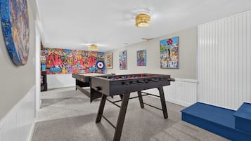 Ein Zimmer mit einem Kicker, einer farbenfrohen Graffiti-Wand und einer blauen Bank.