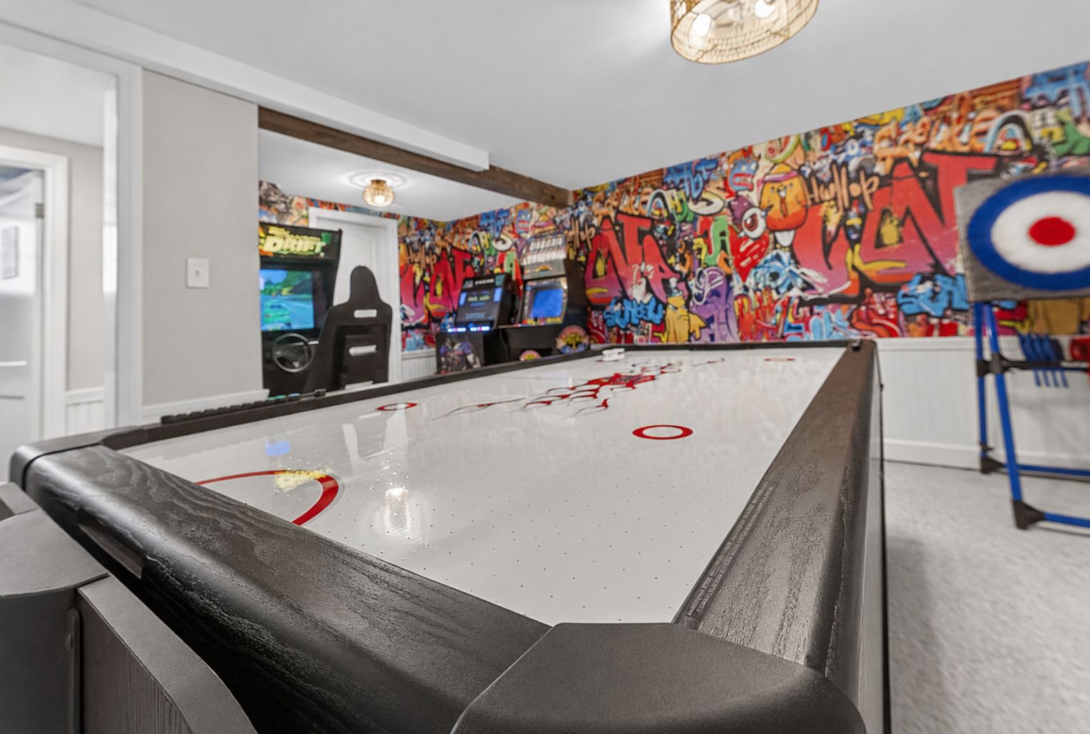 A pool table with graffiti art on the walls, arcade games in the background, and a target on the table.