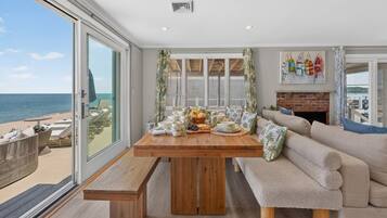 A room with a wooden table set for breakfast, a sofa, and a view of the sea.