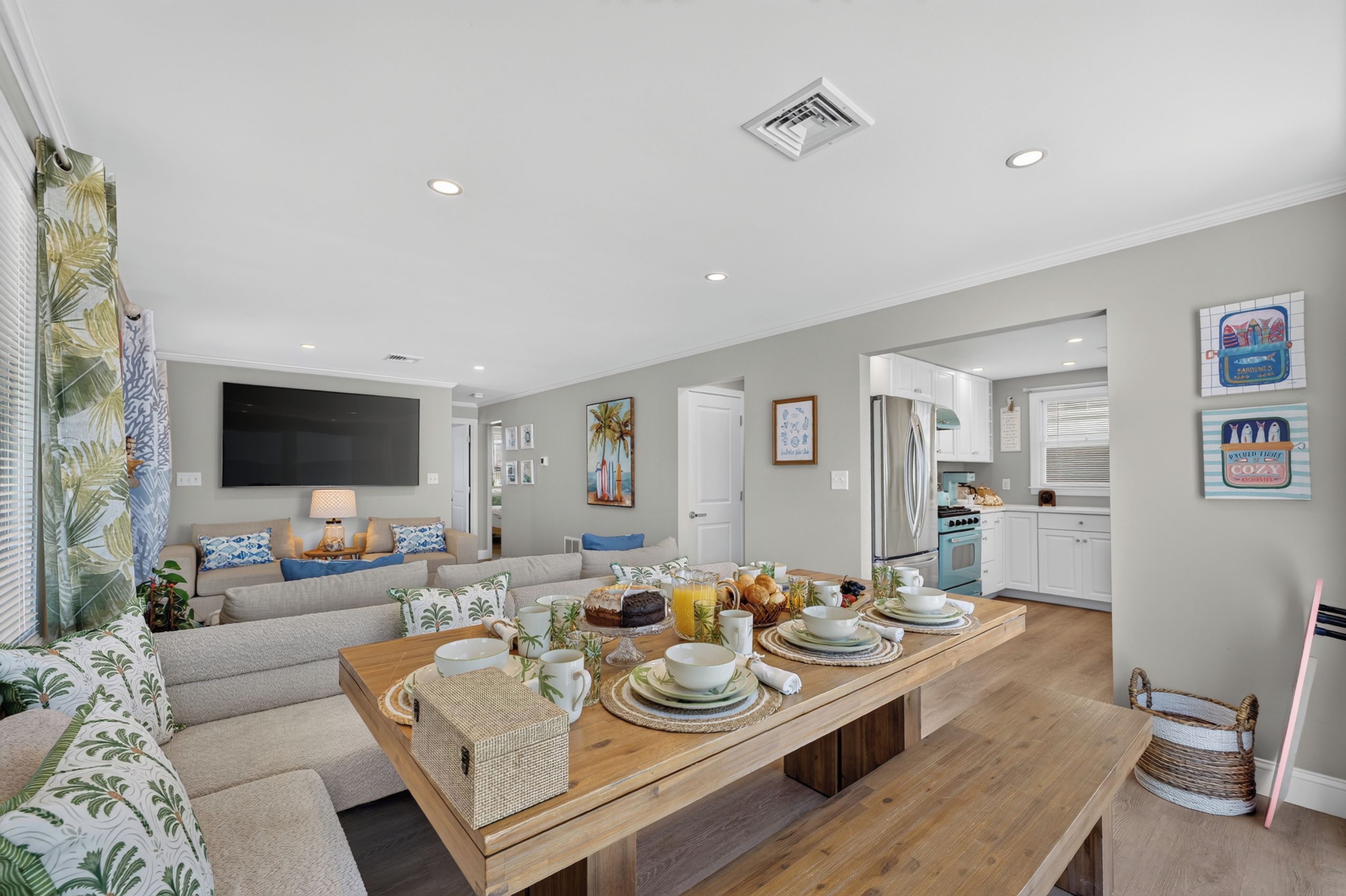 A modern living room with a sofa, a dining table set for breakfast, and a kitchen in the background.