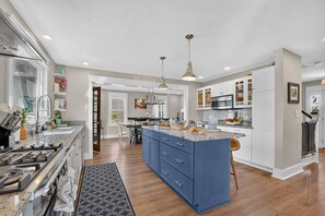 A modern kitchen with a central island, white cabinetry, and a dining area with a table and chairs.
