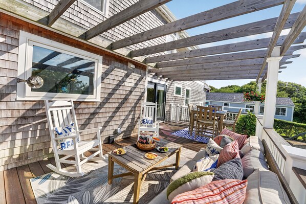 A covered outdoor patio with wooden furniture, a dining table, and a seating area.