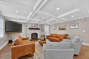 A modern living room with a fireplace, comfortable seating, and artwork on the walls.