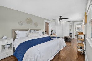 A bedroom with a bed, bedside tables, a ceiling fan, and a nightstand.