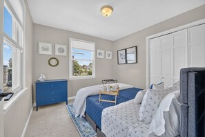 A bedroom with a bed, a dresser, a window, and artwork on the walls.