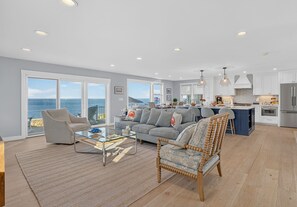 A spacious living area with a view of the ocean, a kitchen with modern appliances, and a dining area.
