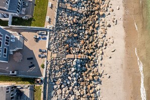 Vista aérea de una playa con una barrera rocosa que separa la arena de los edificios.