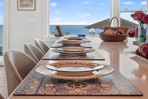 Una mesa de comedor lista para seis personas, con platos, una copa y una cesta de pan.