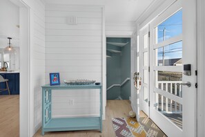 A hallway with a light blue console table, a framed picture, and a patterned rug.