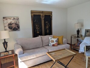 Ein Wohnzimmer mit einer Couch, einem Couchtisch, einer Lampe und einem gerahmten Bild an der Wand.