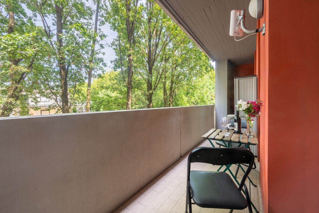 A balcony with a table and chairs, overlooking a forested area.