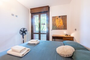 A bedroom with a bed, a desk, a fan, and a painting. - A cozy and comfortable 47 sqm apartment, perfect for four people, located on the first floor of a building with an elevator.The property is situated in a quiet yet strategic area near Parma's city center; the train station, airport, and highway entrance  (Parma)