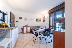 A dining area with a table set for four, a kitchen area with a refrigerator, and a window with a view. - A cozy and comfortable 47 sqm apartment, perfect for four people, located on the first floor of a building with an elevator.The property is situated in a quiet yet strategic area near Parma's city center; the train station, airport, and highway entrance  (Parma)
