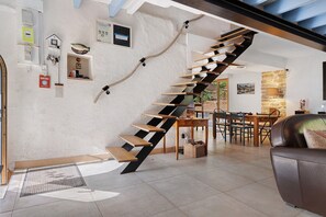 Een modern interieur met een houten trap, een eethoek en een zithoek.