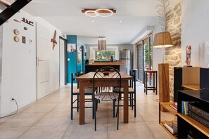 A modern kitchen with a central island, a dining area with a wooden table and chairs, and a bookshelf with books and decorative items. - Characterful House in the Gulf of Morbihan with Private Terrace and Garden (Sarzeau)
