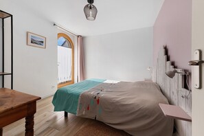 Un dormitorio con una cama, una mesa de madera, una ventana con cortinas y una lámpara en el techo.