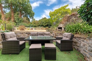 An outdoor seating area with wicker furniture and a glass-top table. - Characterful House in the Gulf of Morbihan with Private Terrace and Garden (Sarzeau)