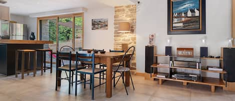 Cocina moderna con zona de comedor, pared de piedra y obras de arte.