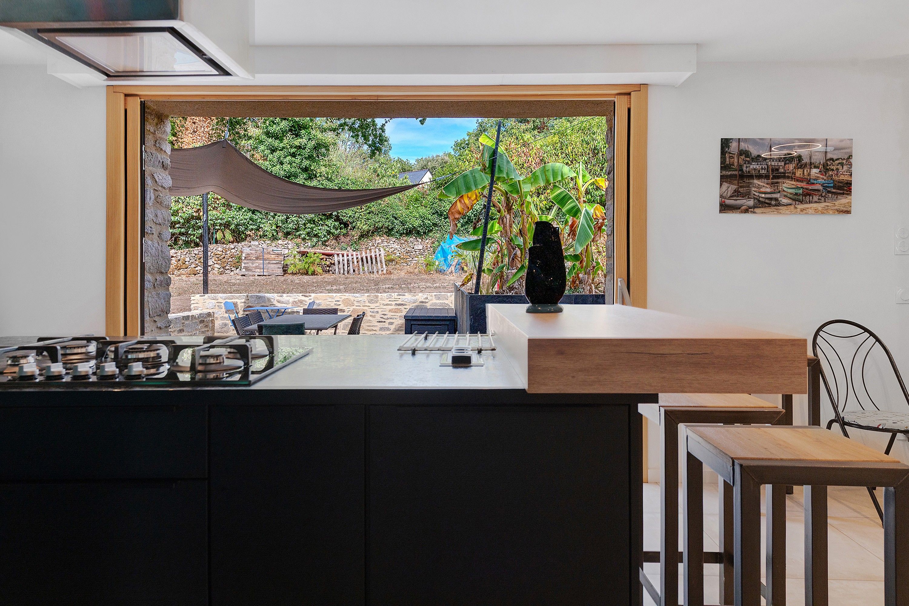 A modern kitchen with a large window, a dining area with a table and chairs, and a view of the outdoors.