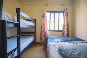 A room with bunk beds, a window with floral curtains, and a bed with a patterned bedspread. - Beautiful 2-bedroom apartment in gated and secure community (Lusaka)