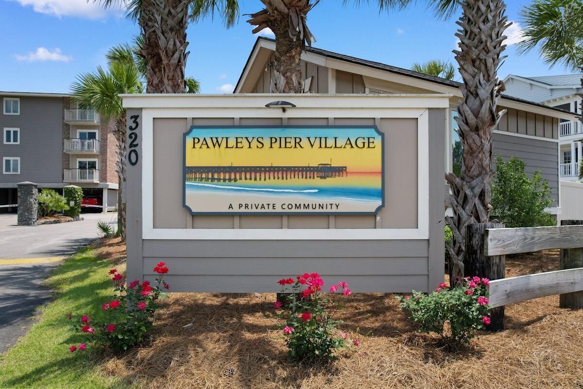 A sign for Pawley's Pier Village, a private community, with a view of a pier and beach.
