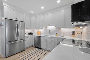 A modern kitchen with white cabinetry, stainless steel appliances, and a marble countertop. - 3 Bedroom Oceanfront: Stargazing from the 2nd Flr (Pawleys Island)