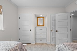 A bedroom with two beds, a white wardrobe, and a mirror above a dresser. - 3 Bedroom Oceanfront: Stargazing from the 2nd Flr (Pawleys Island)