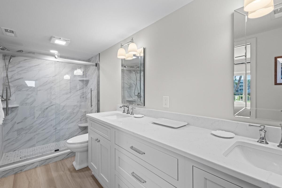 A modern bathroom with a walk-in shower, a toilet, and a vanity with a large mirror.