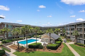 A multi-story hotel with a swimming pool surrounded by palm trees and a small building. - 3 Bedroom Oceanfront: Stargazing from the 2nd Flr (Pawleys Island)