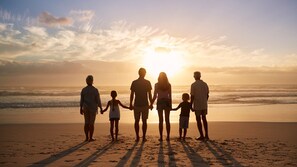 Eine Familie hält am Strand bei Sonnenuntergang Händchen.