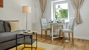 A modern living room with a sofa, a coffee table, a dining table with chairs, and a window with curtains. - "Poeler Küstenkoje" Vacation Rental for 4 People (Insel Poel / OT Kirchdorf)