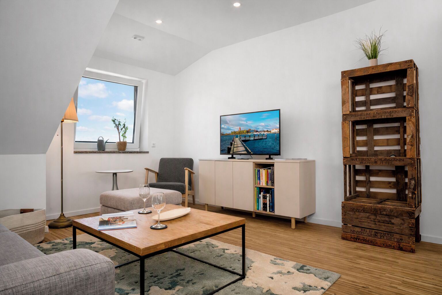 Ein modernes Wohnzimmer mit Fernseher, Bücherregal, Sofa und Couchtisch.