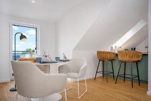 Eine moderne Küche mit Essbereich, ausgestattet mit einem großen Fenster, einer Bar mit Barhocker und einem Esstisch mit Stühlen.