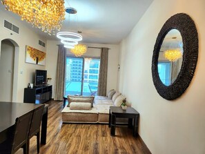 A modern living room with a sofa, a dining table, and a large mirror. - Bright 2-bedroom apartment with AC in fantastic Dubai location (Dubai)