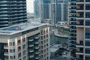 Un immeuble de grande hauteur doté de nombreux balcons, offrant une vue sur le front de mer et comprenant une promenade piétonne le long de la berge.