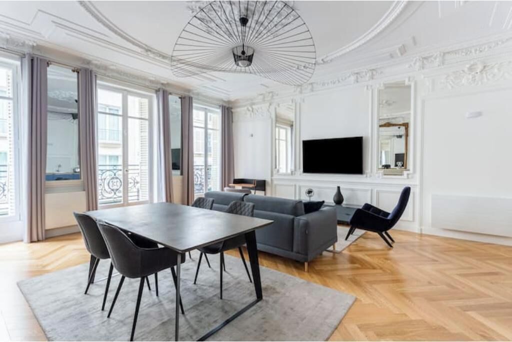 A modern living room with a dining table, sofa, and TV.