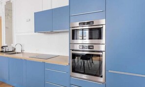 A kitchen with blue cabinets, a stainless steel oven, and a wooden countertop. - Very spacious, recently renovated apartment near Madeleine (Île-de-France)
