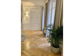 A hallway with a wooden floor, white doors, and a potted plant. - Very spacious, recently renovated apartment near Madeleine (Île-de-France)