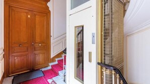 Eine hölzerne Doppeltür, eine weiße Tür mit Fenster und eine Metall-Wendeltreppe.