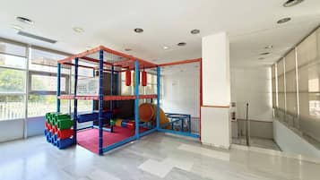 Un área de juegos con una estructura para escalar, colchonetas blandas y coloridos contenedores de almacenamiento.