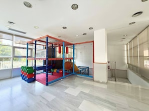 A play area with a climbing structure, soft play mats, and colorful storage bins.