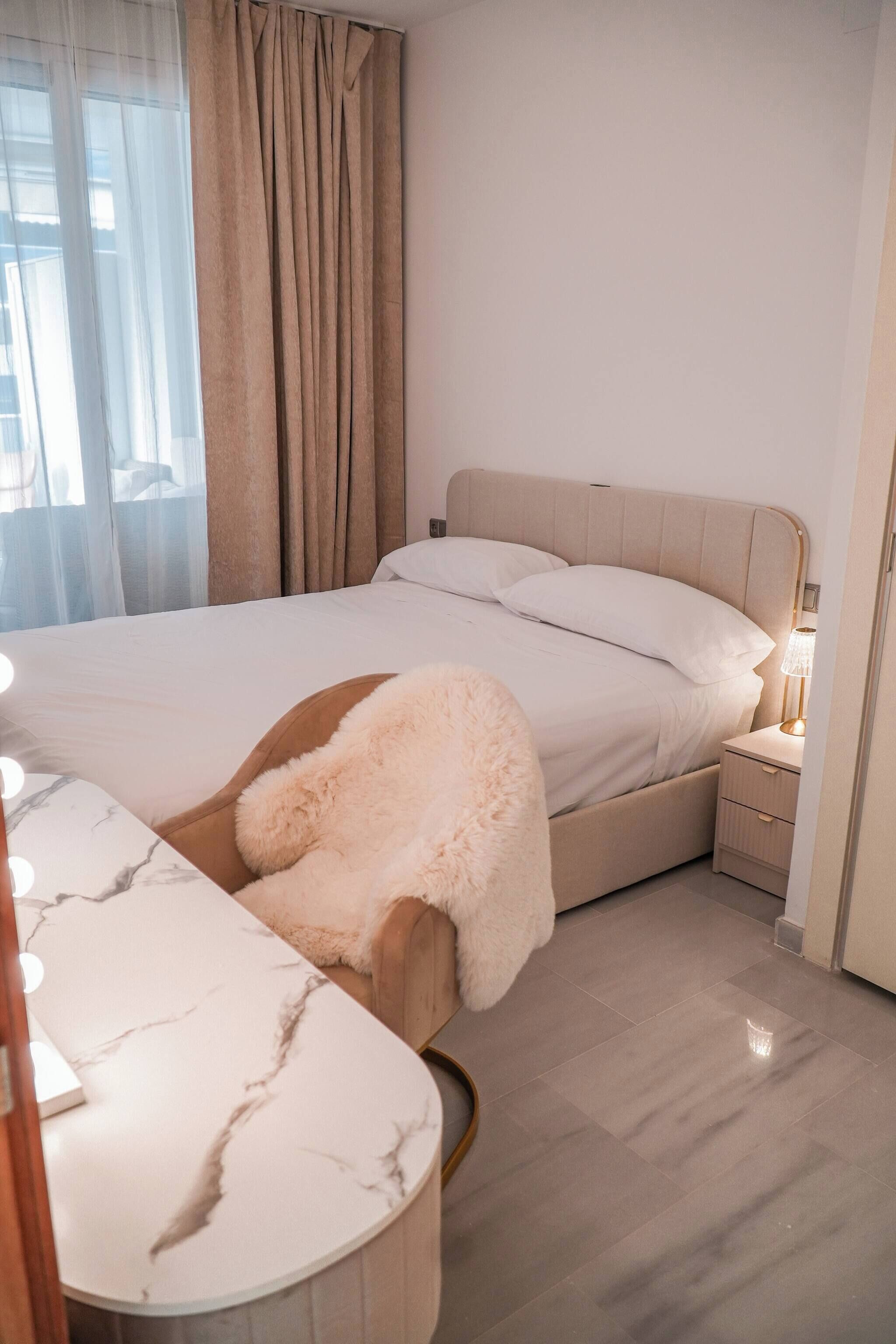 Une chambre à coucher comprenant un lit, une table de chevet et une coiffeuse avec un miroir.