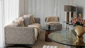 Un salon moderne comprenant un canapé, un fauteuil, une table basse en verre et des objets de décoration.