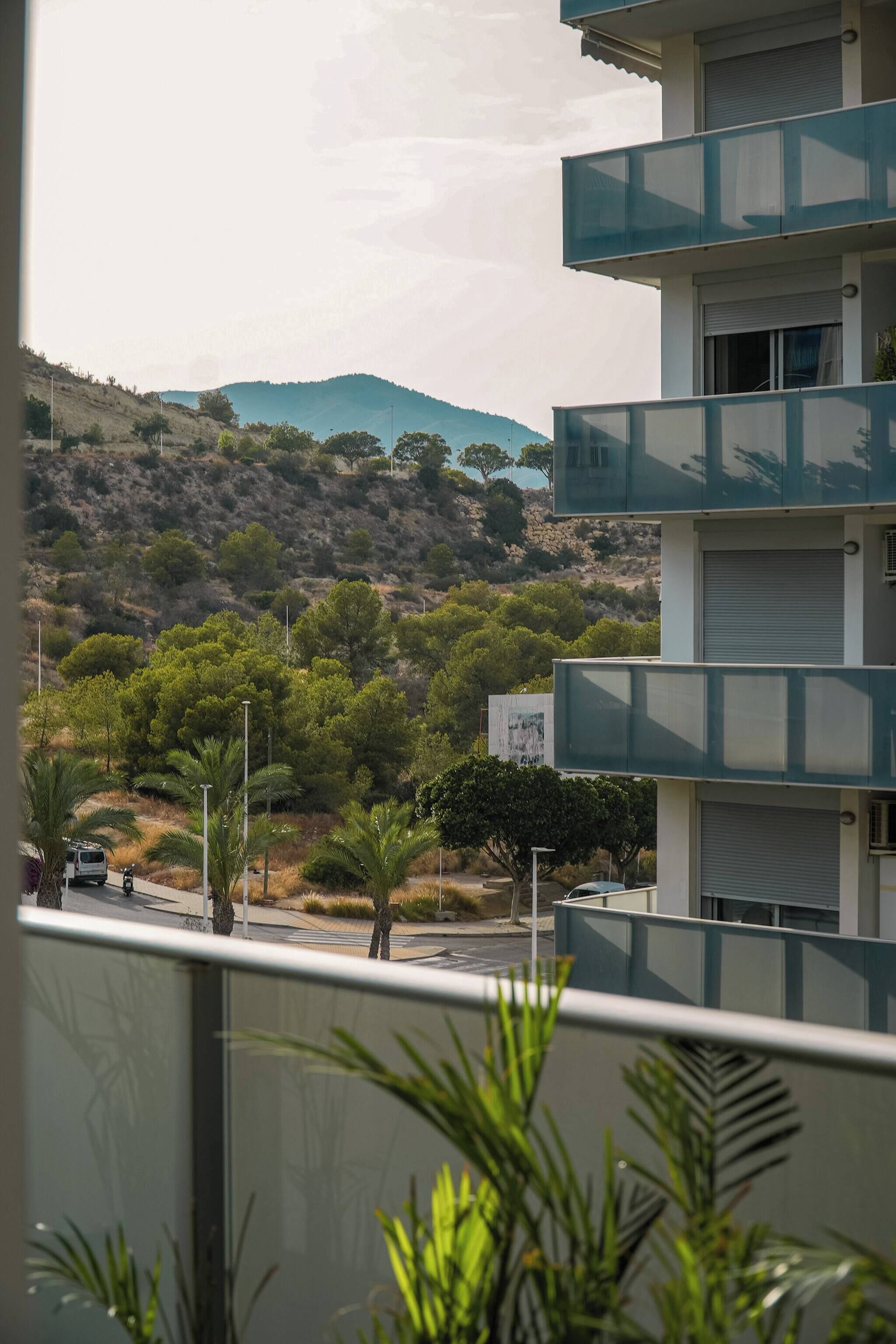 A multi-story building with balconies overlooking a hilly landscape with sparse vegetation.